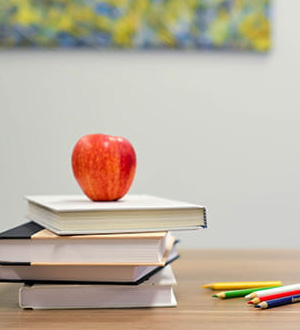 Books, pencils, and an apple in a classroom